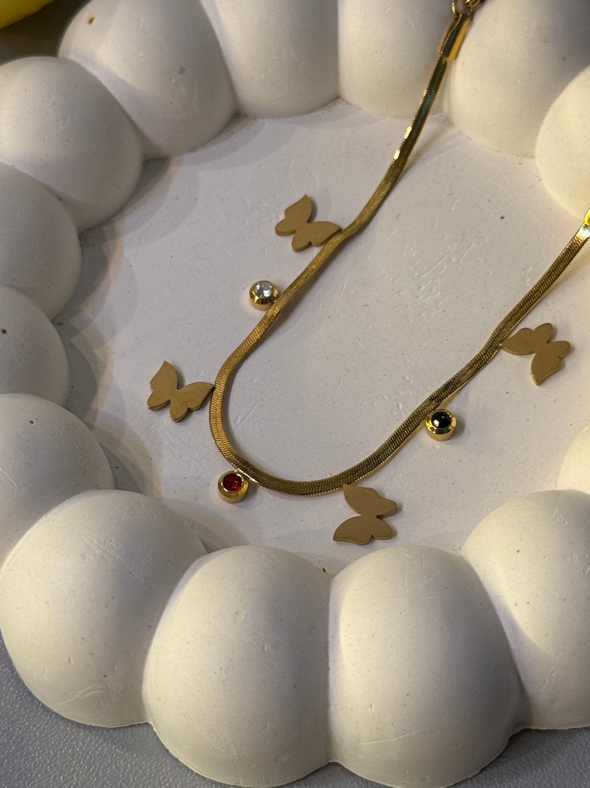 Close-up of a decorative wall clock with white face, gold hands, and butterfly designs.