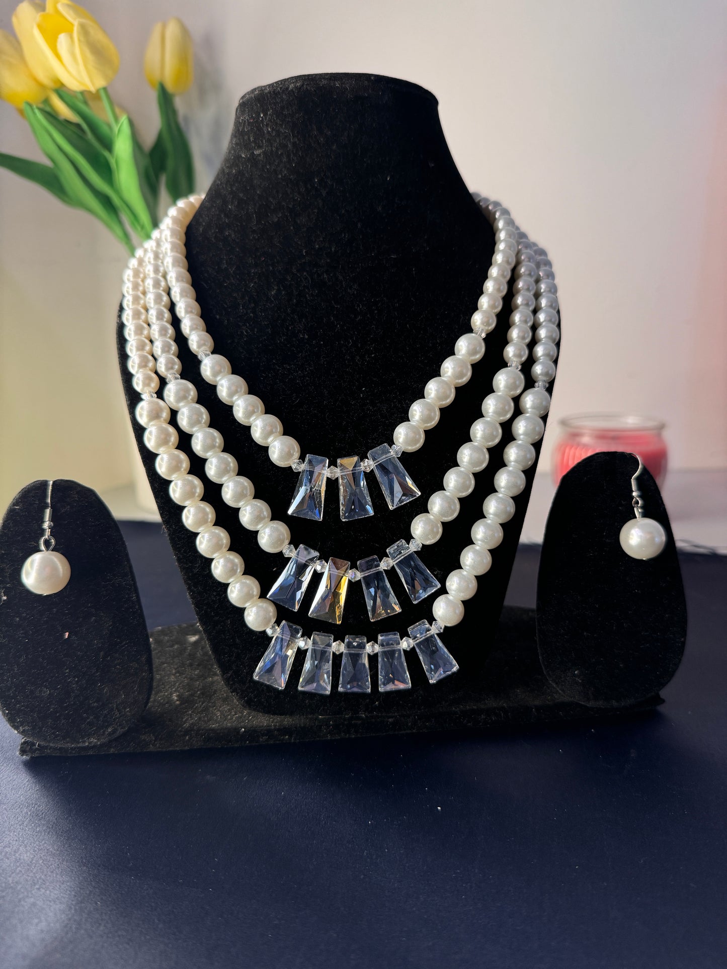 Pearl and crystal earring on a black stand with a blurred background
