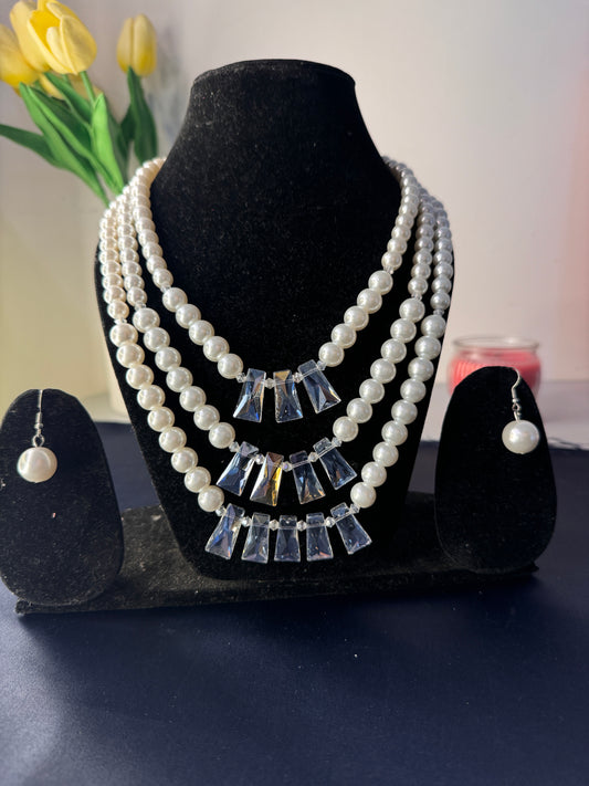 Pearl and crystal earring on a black stand with a blurred background