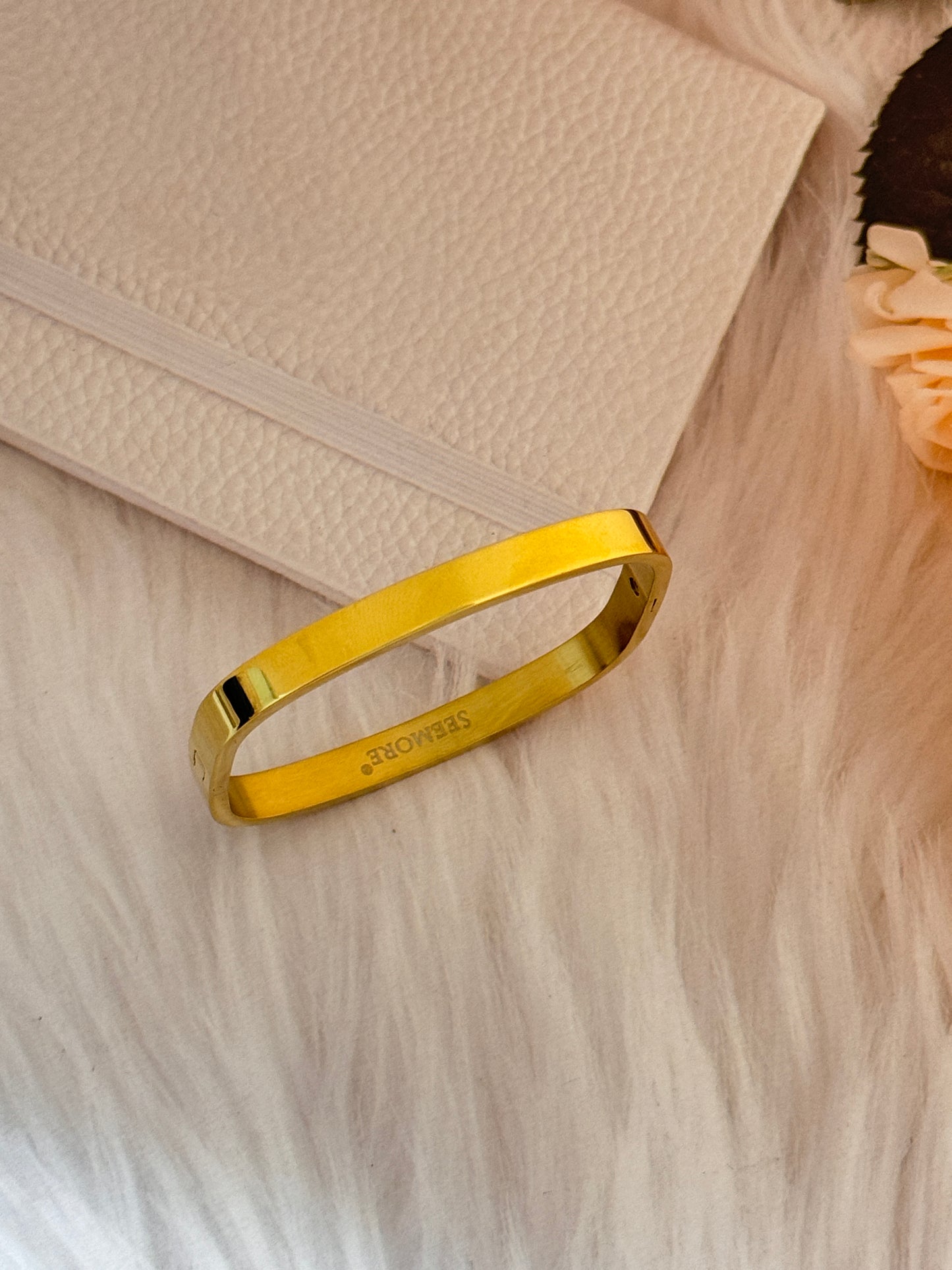 Gold bracelet on a textured beige surface