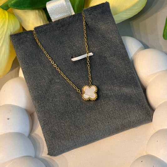 Gold necklace with a star-shaped pendant on a gray surface with flowers in the background