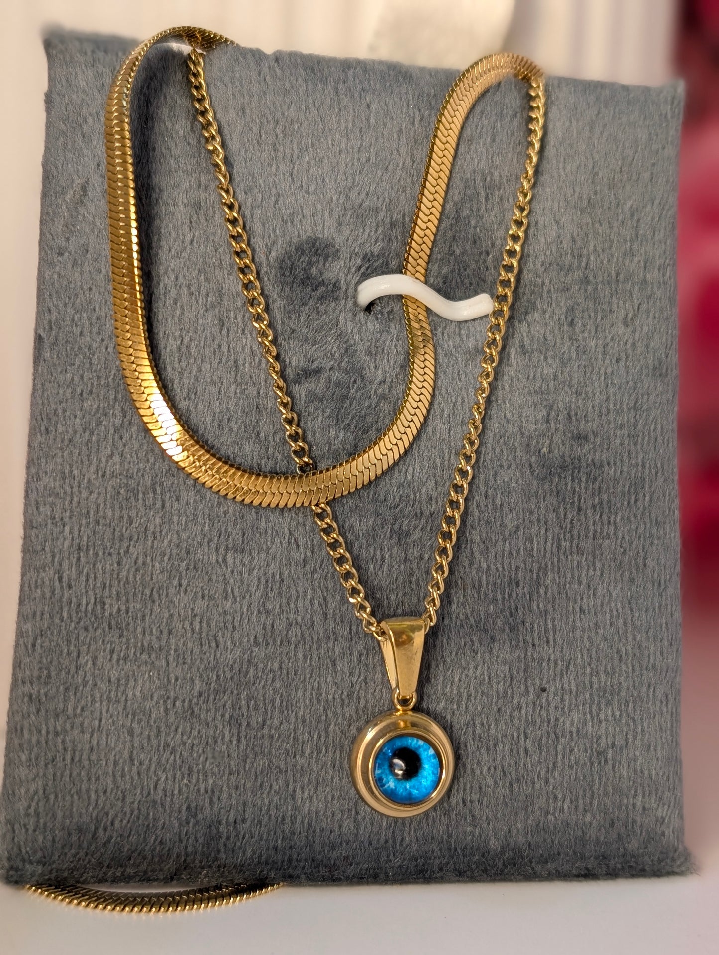 Gold chain necklace with a blue pendant on a gray surface