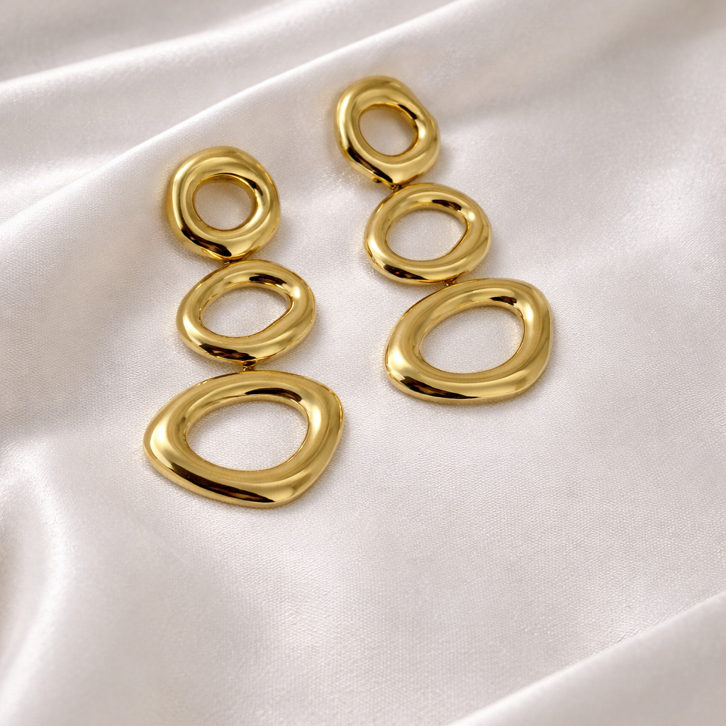 Gold hoop earrings on a white satin background
