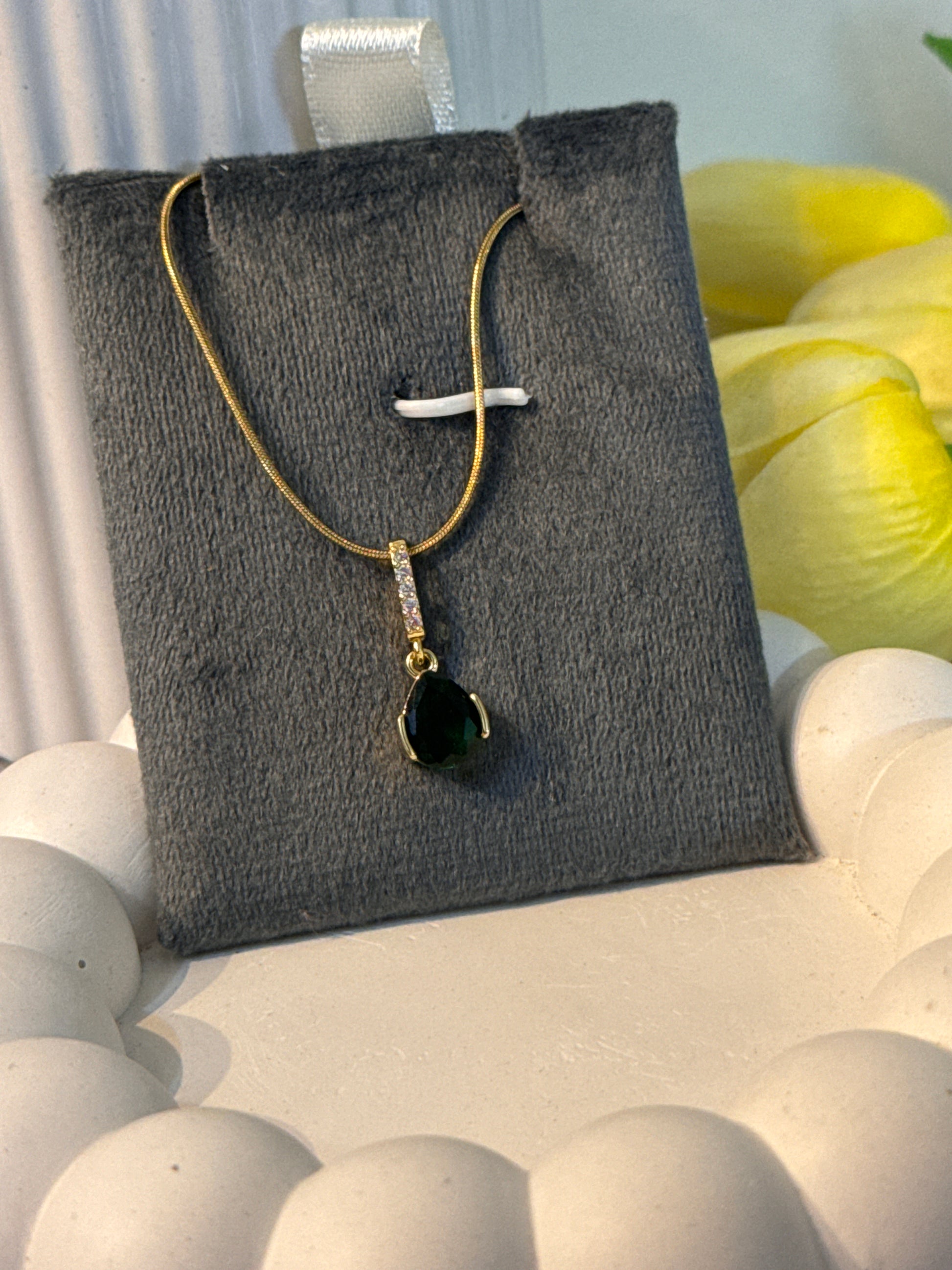 Necklace with a black pendant on a gray fabric surface