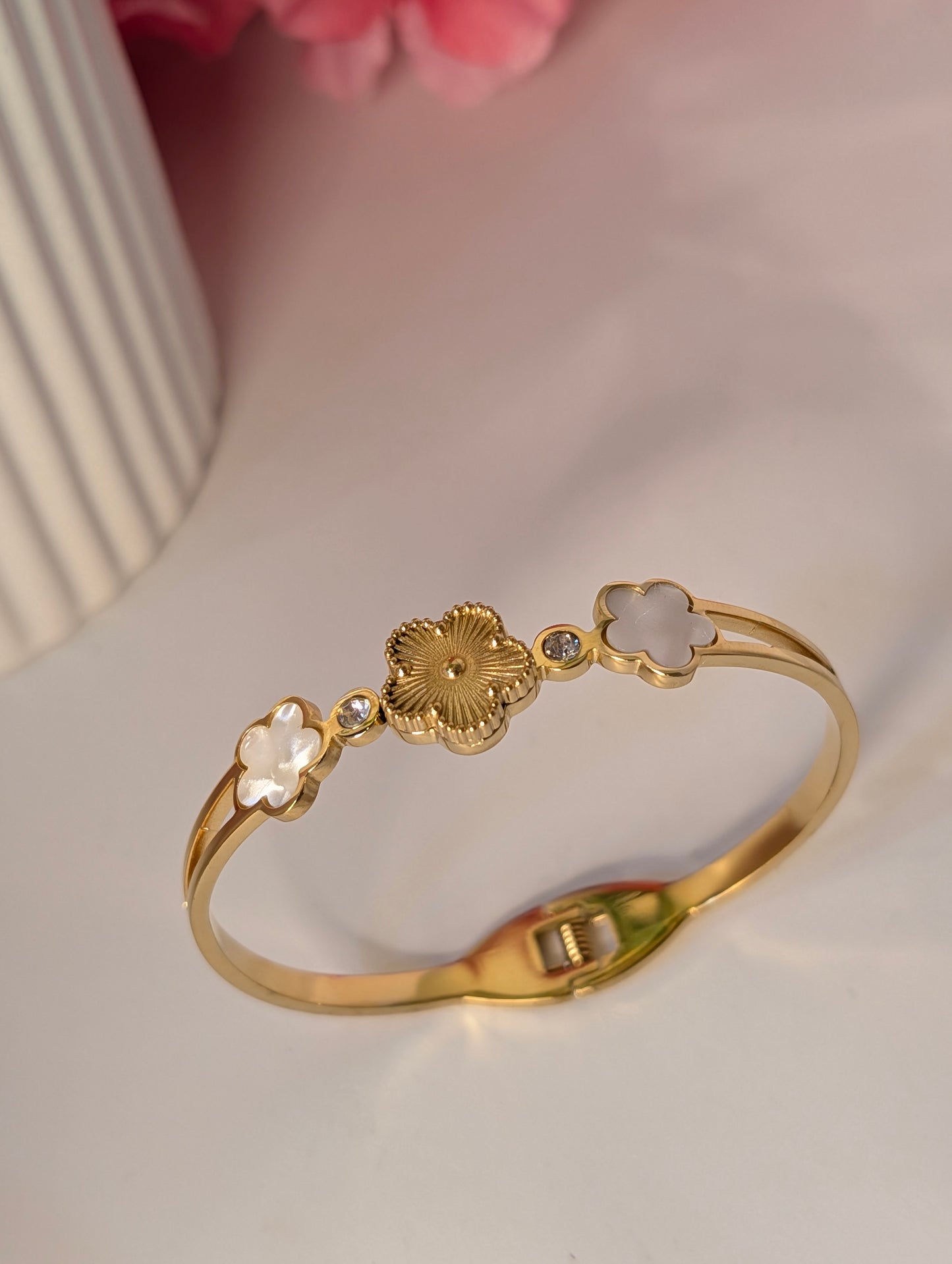Gold bracelet with floral designs on a light background