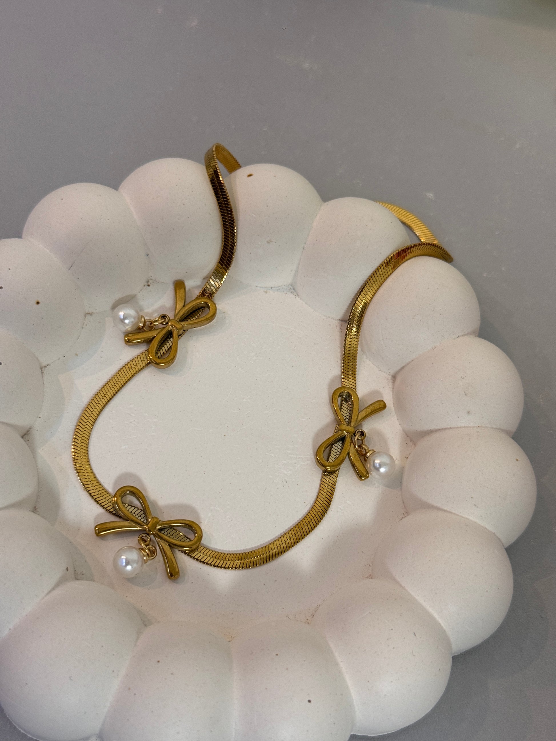 Gold bracelet with pearl accents on a white stone surface