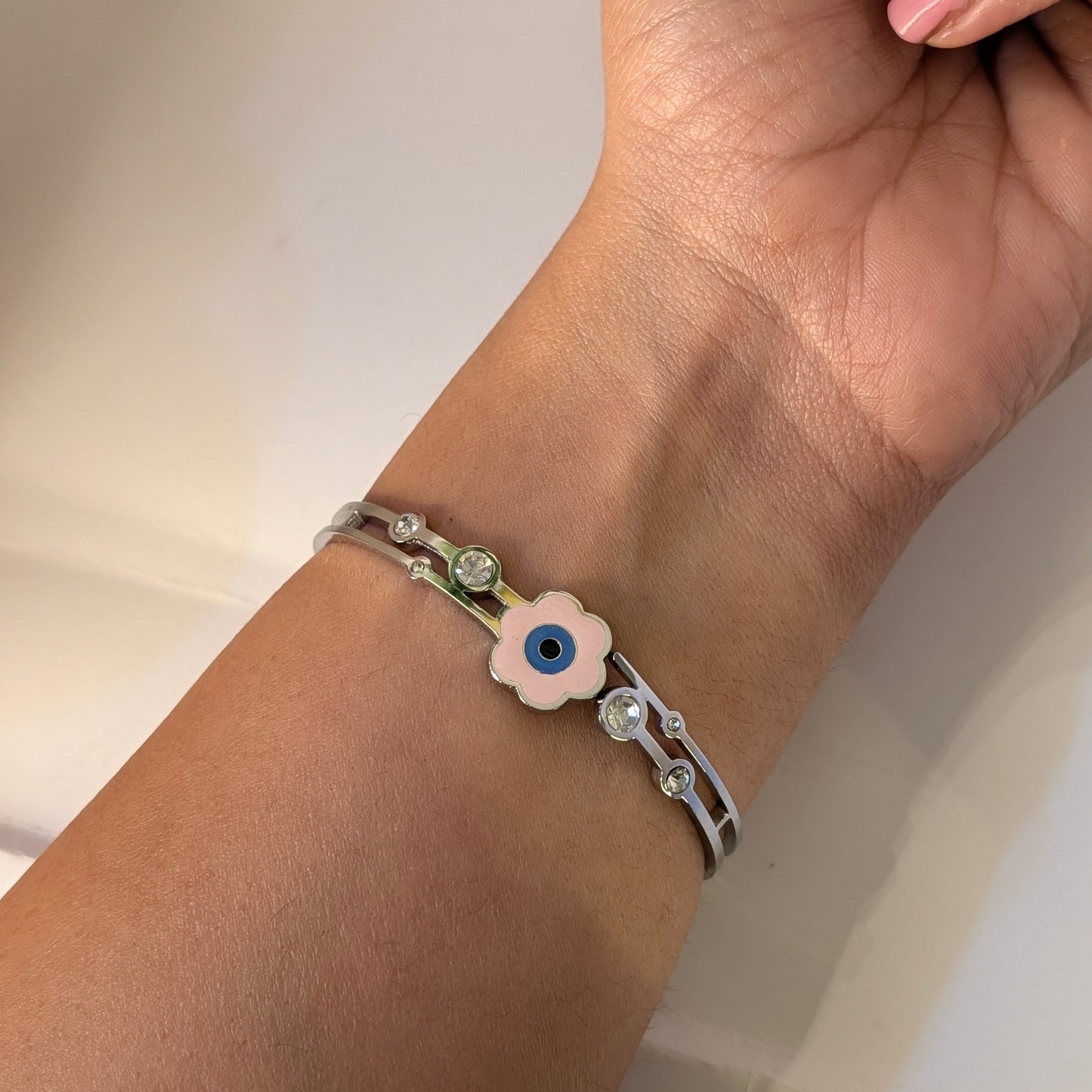 Close-up of a wrist wearing a silver bracelet with a floral design on a light background