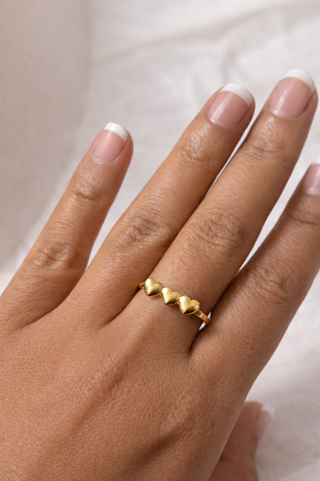Gold ring on a hand with a neutral background