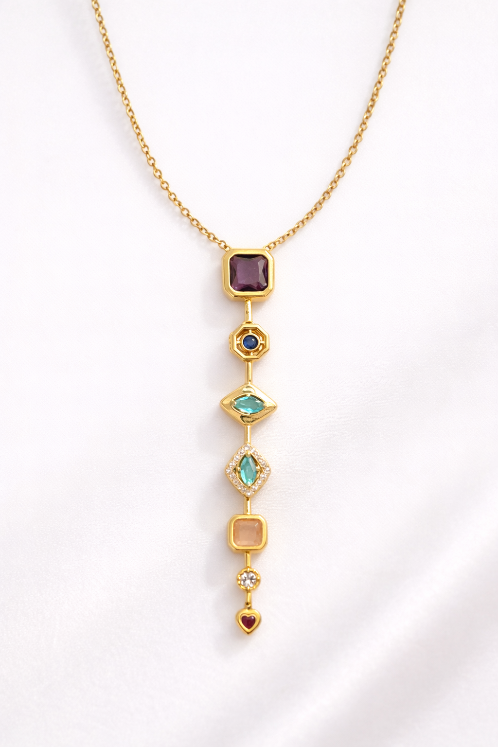 Gold necklace with various gemstones on a white background
