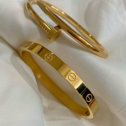 Two gold bracelets on a white fabric background