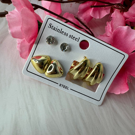 A set of earrings displayed on a card, featuring a combination of golden and silver-colored designs.