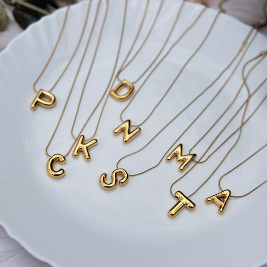 Gold necklaces with letter pendants on a white shell