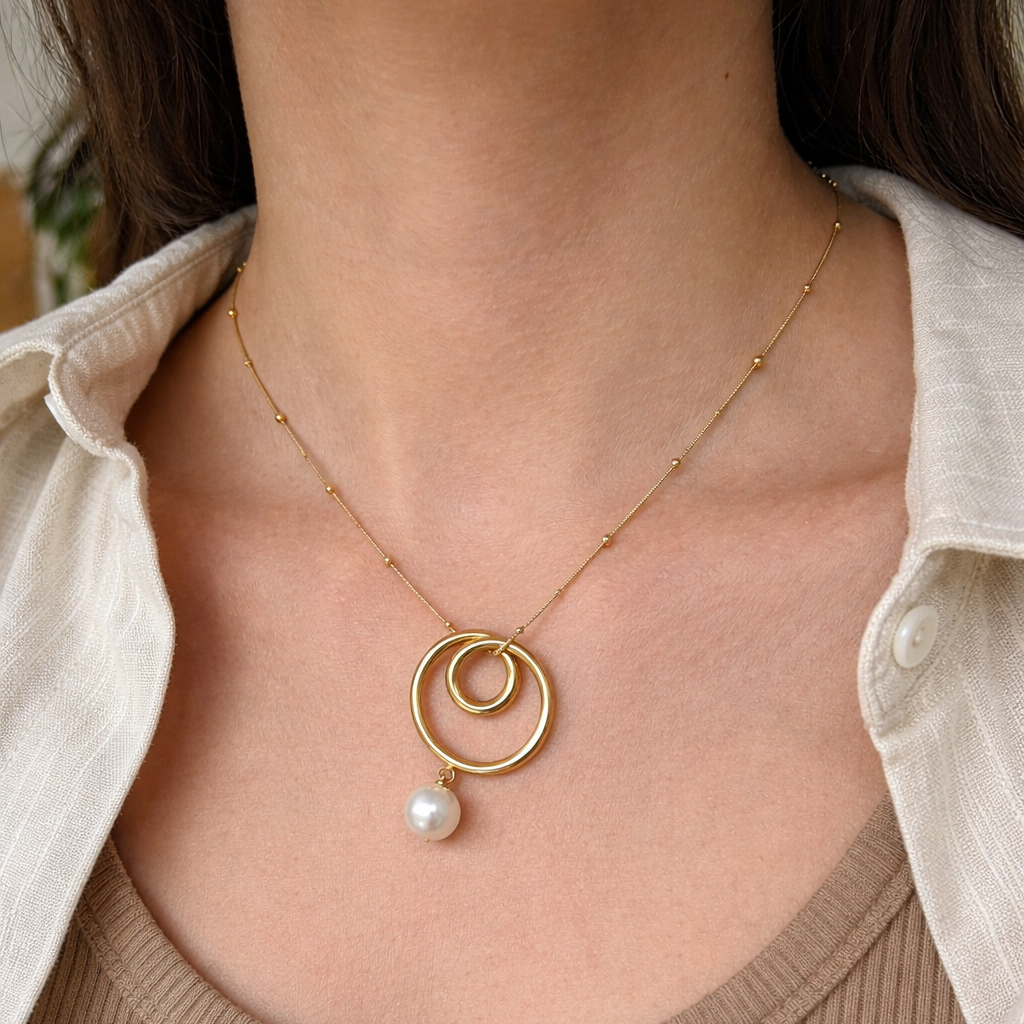 Gold necklace with a pearl pendant worn by a person