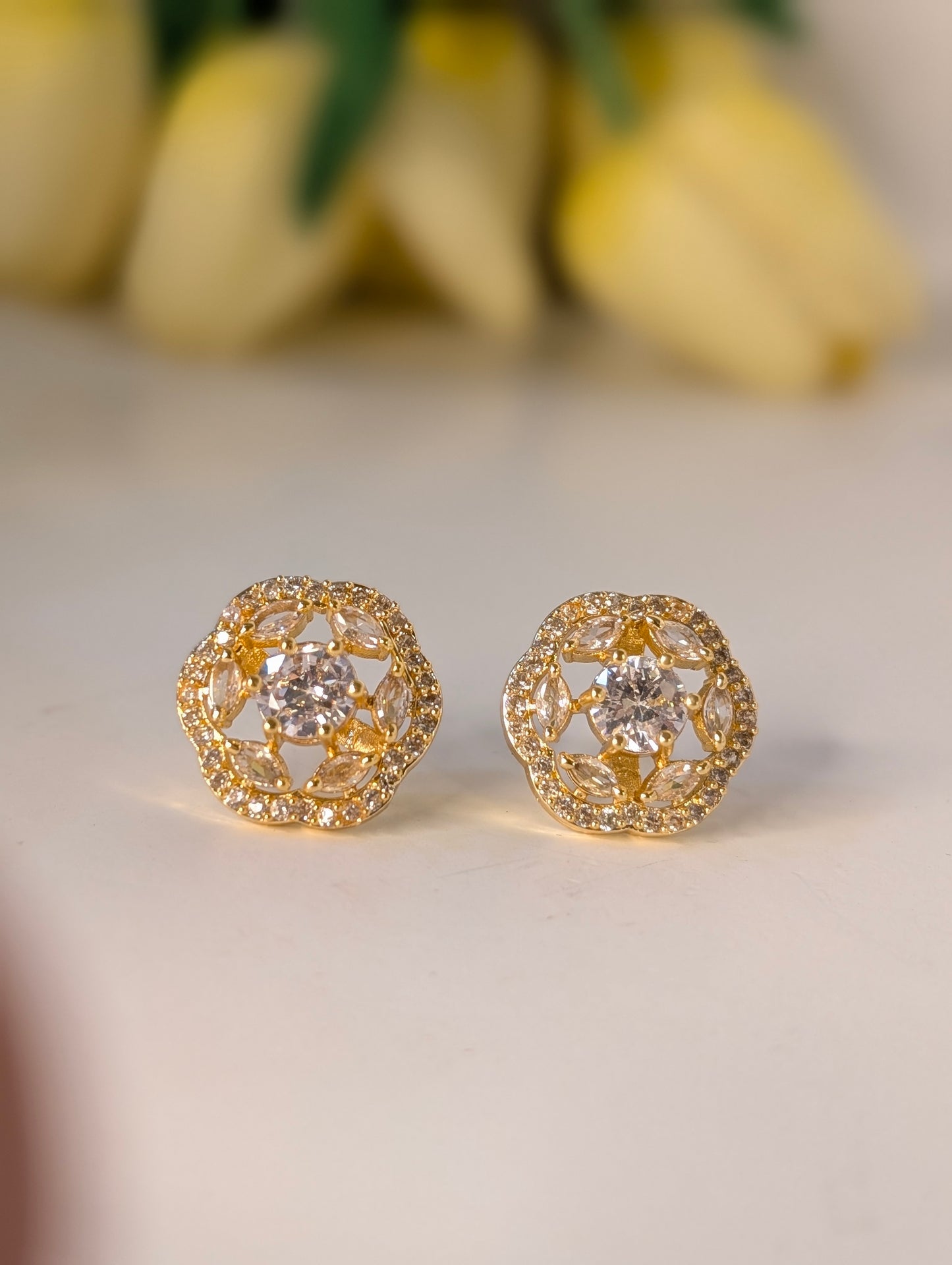 Gold earrings with intricate design on a light background