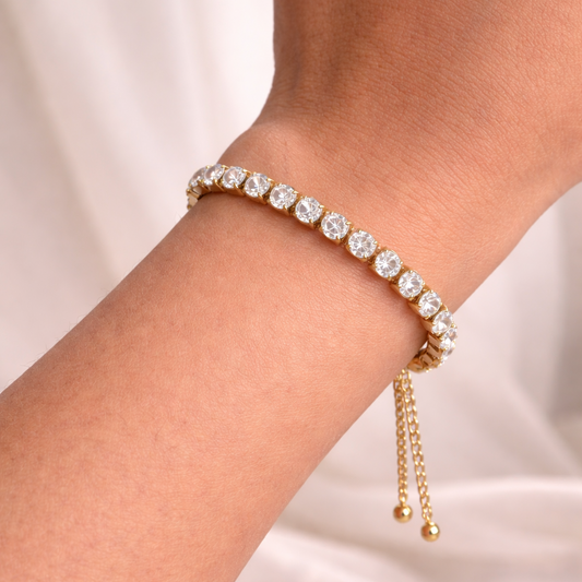 Gold bracelet with clear stones on a wrist against a light background