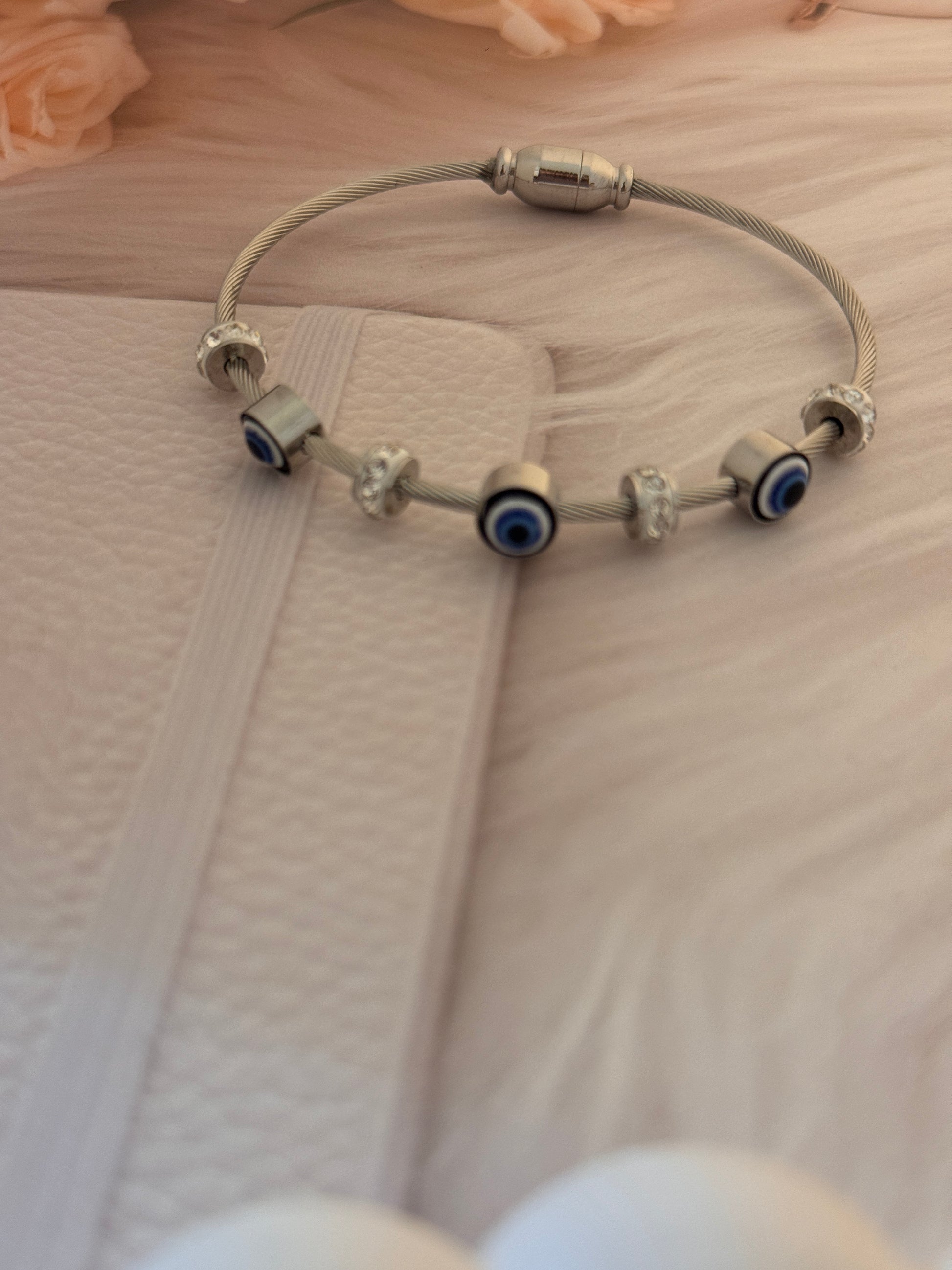 Silver bracelet with blue evil eye charms on a textured surface