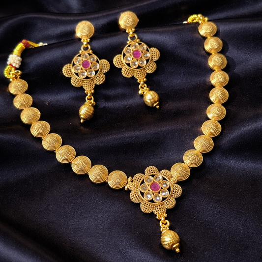 Gold necklace and earrings set on a dark fabric background