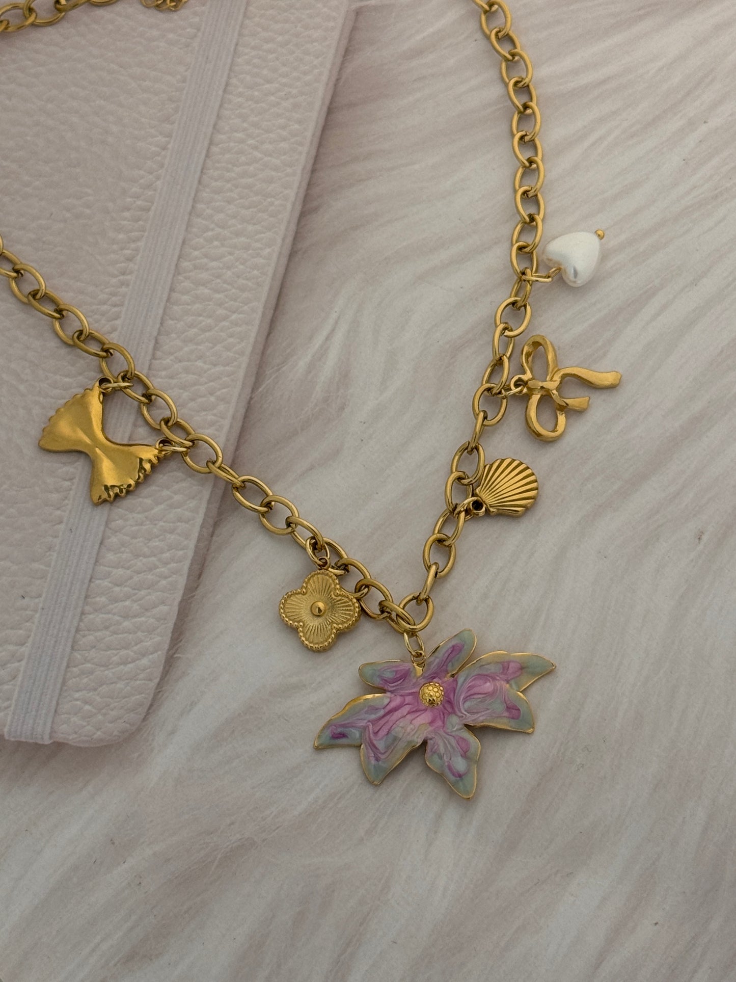 Gold bracelet with floral and shell charms on a textured surface