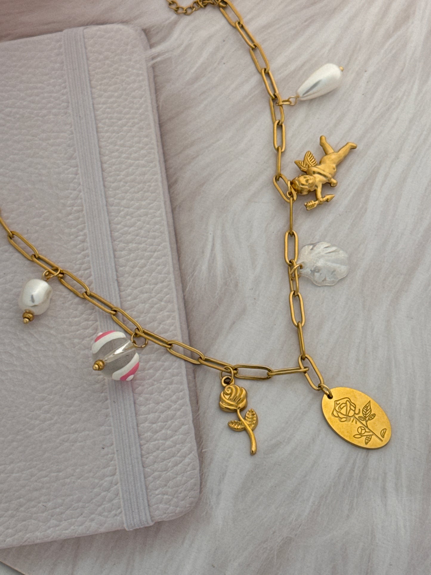 Gold bracelet with various charms on a textured surface