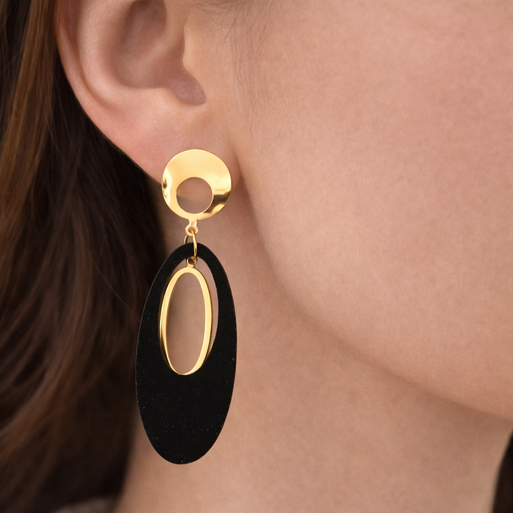 Black earrings with gold accents worn by a person