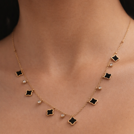 Necklace with black clover-shaped pendants on a person wearing a white top.