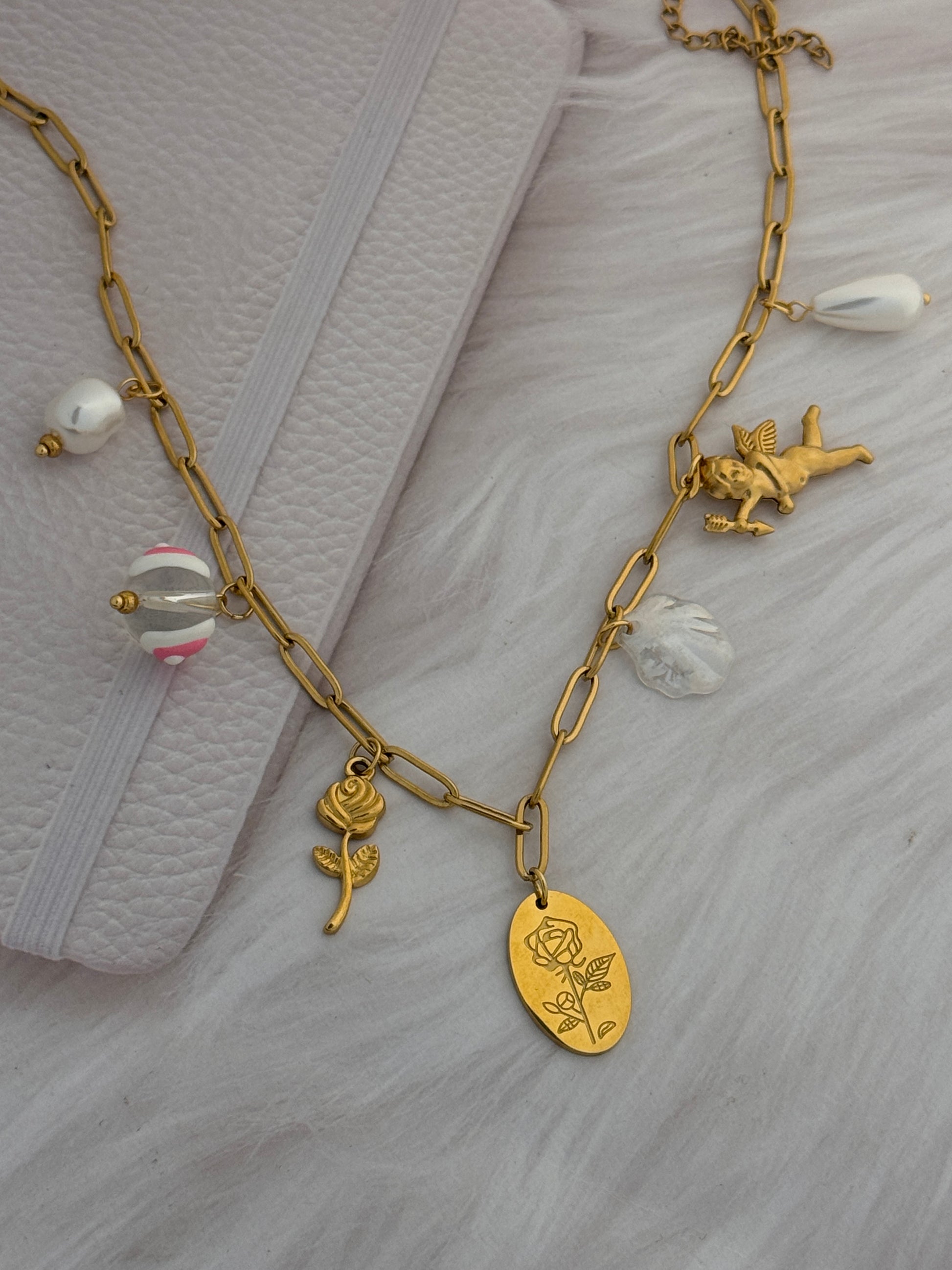 Gold bracelet with various charms on a textured white surface