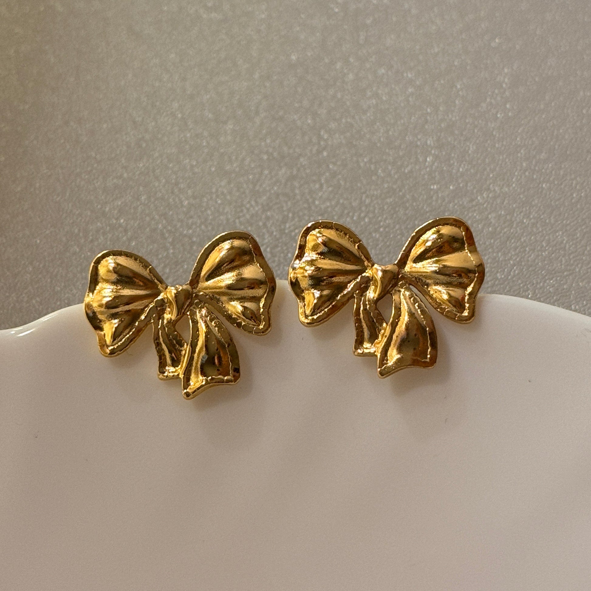 Pair of gold earrings on a light gray background