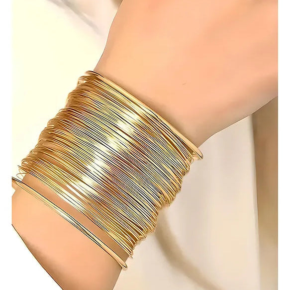 Gold bracelet on a person's wrist with a plain background