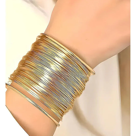 Gold bracelet on a person's wrist with a plain background