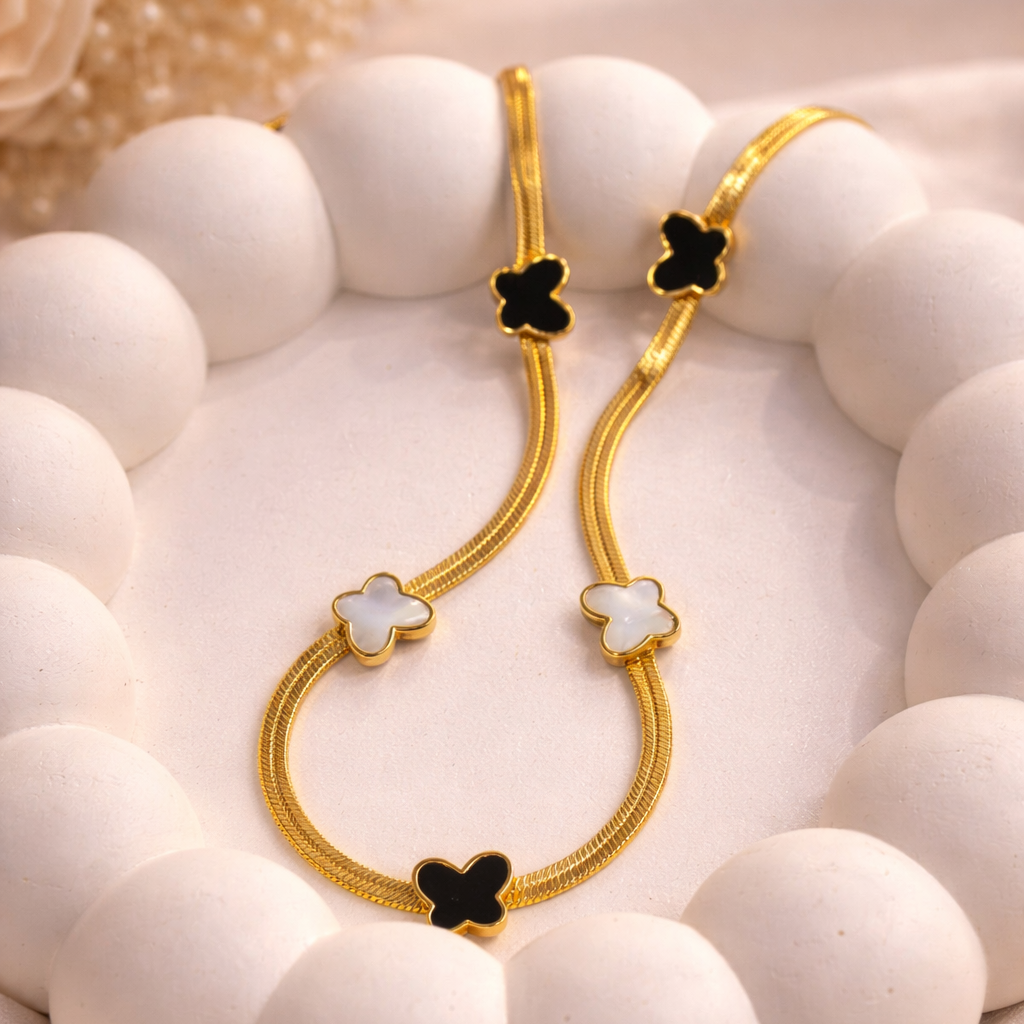 Gold hoop earrings with black and white accents on a white stone surface.