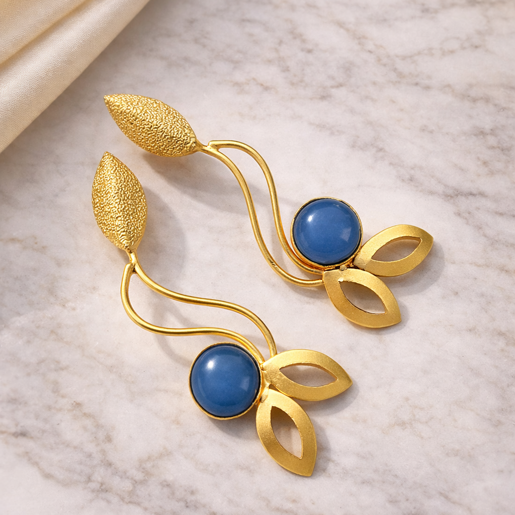 Gold earrings with blue stones on a marble surface