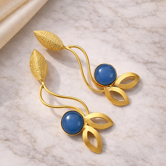 Gold earrings with blue stones on a marble surface