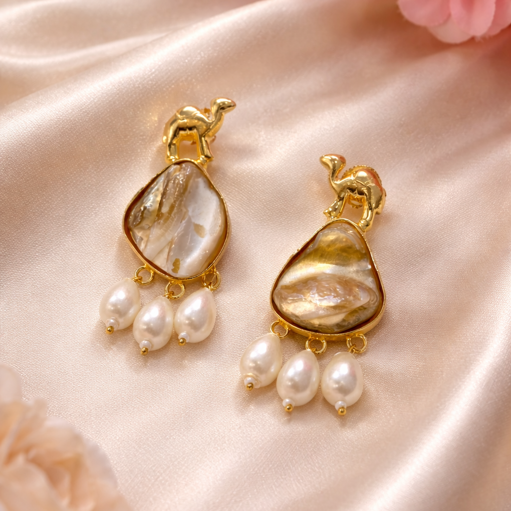Gold earrings with pearl drops on a satin surface