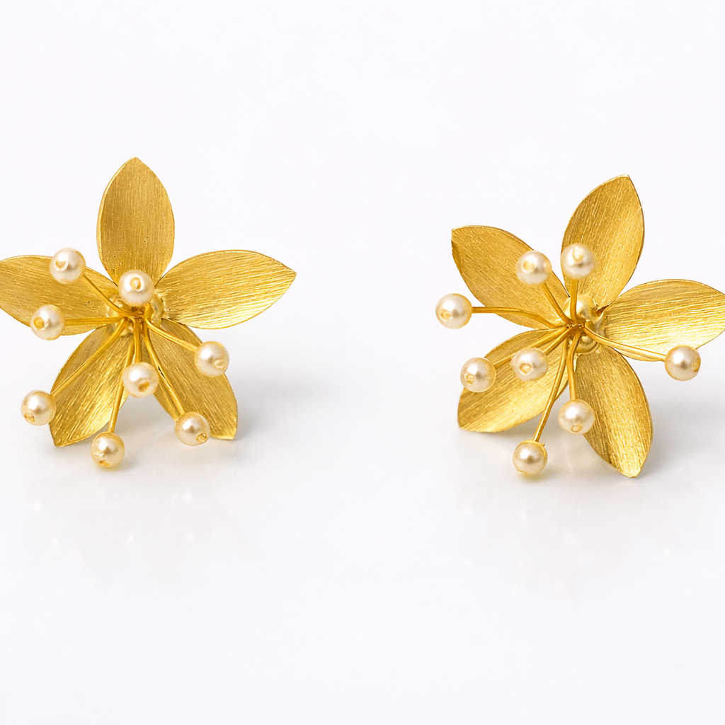 Pair of gold flower-shaped earrings with pearl centers on a white background