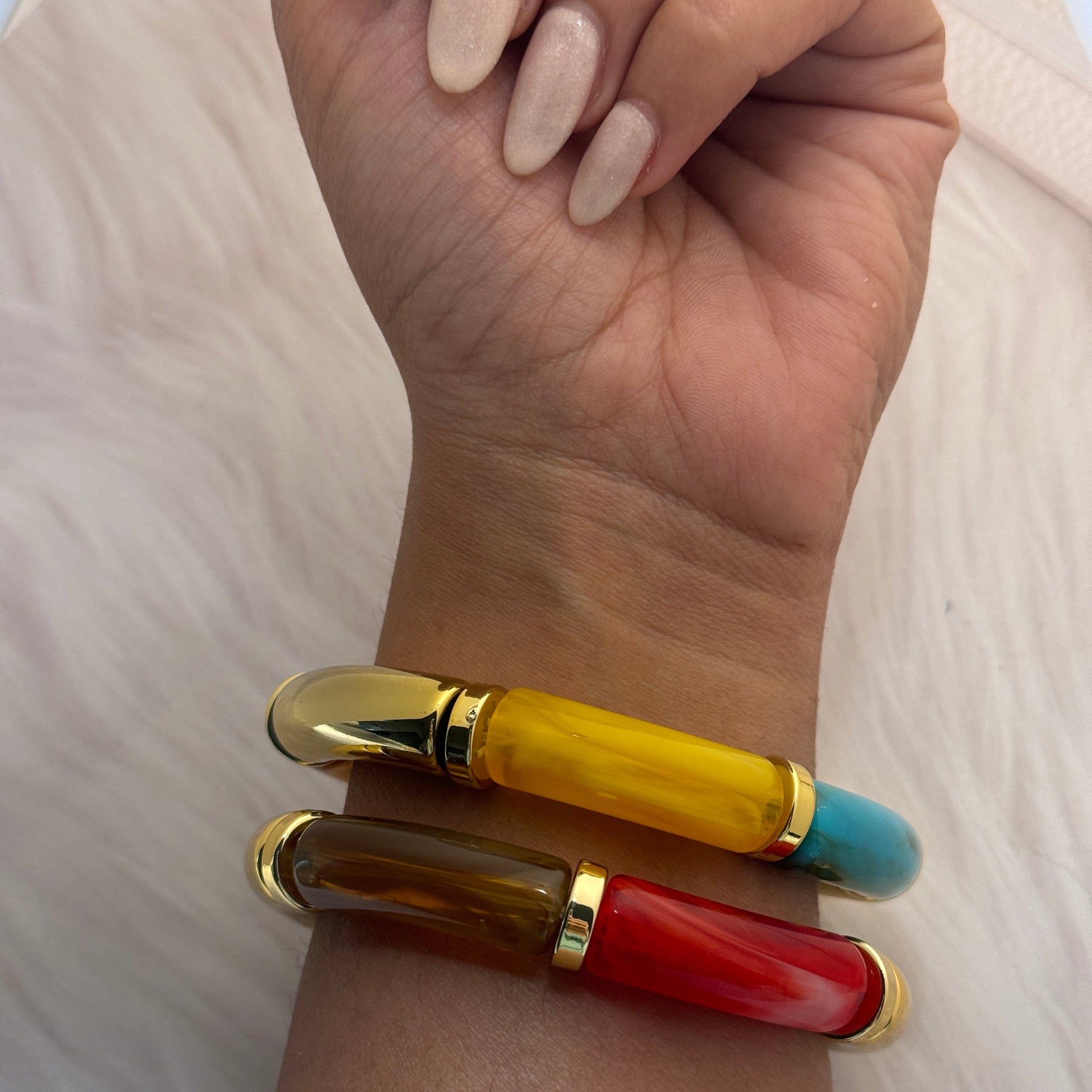 Two colorful bangles on a wrist with a neutral background