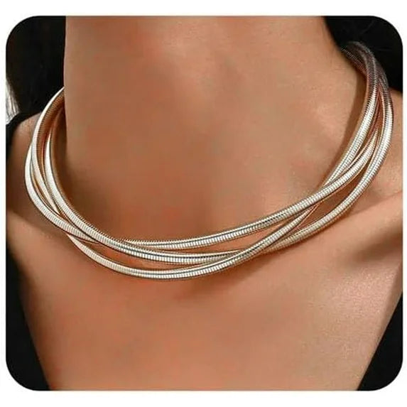 Silver necklace on a person's neck with a plain background