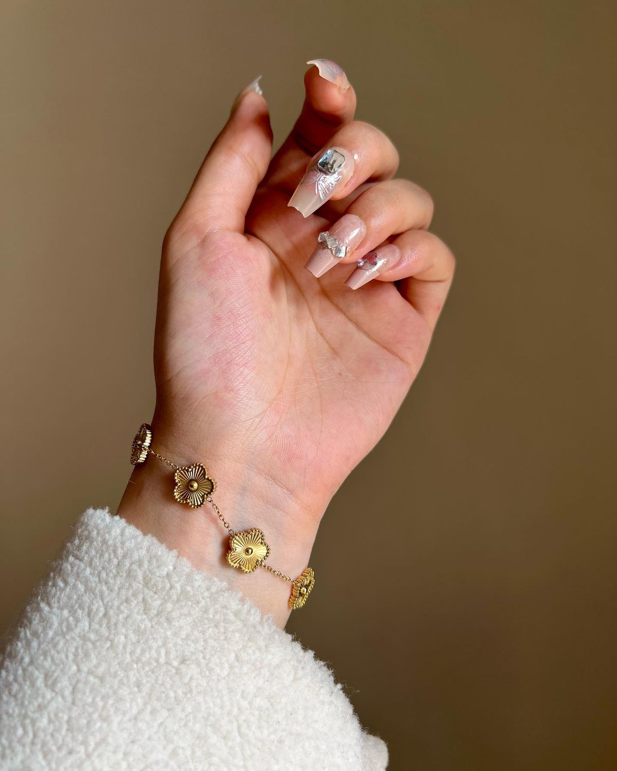 Hand wearing a gold bracelet with a blurred background