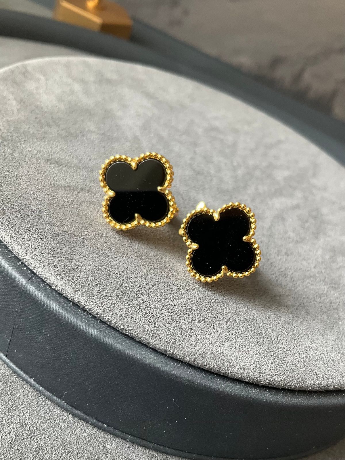Black earrings with gold accents on a gray surface