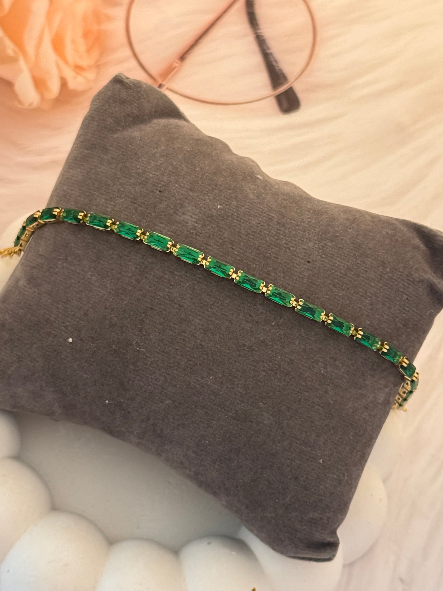 Green beaded necklace on a gray pillow with blurred background