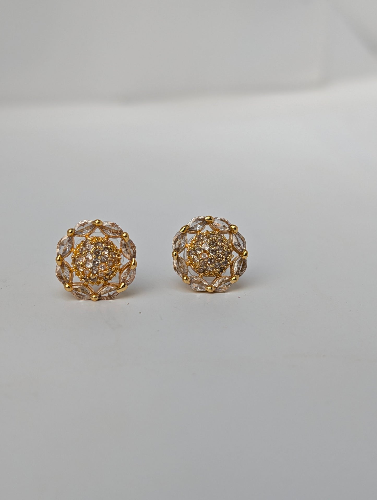 Pair of gold and crystal earrings on a light gray background