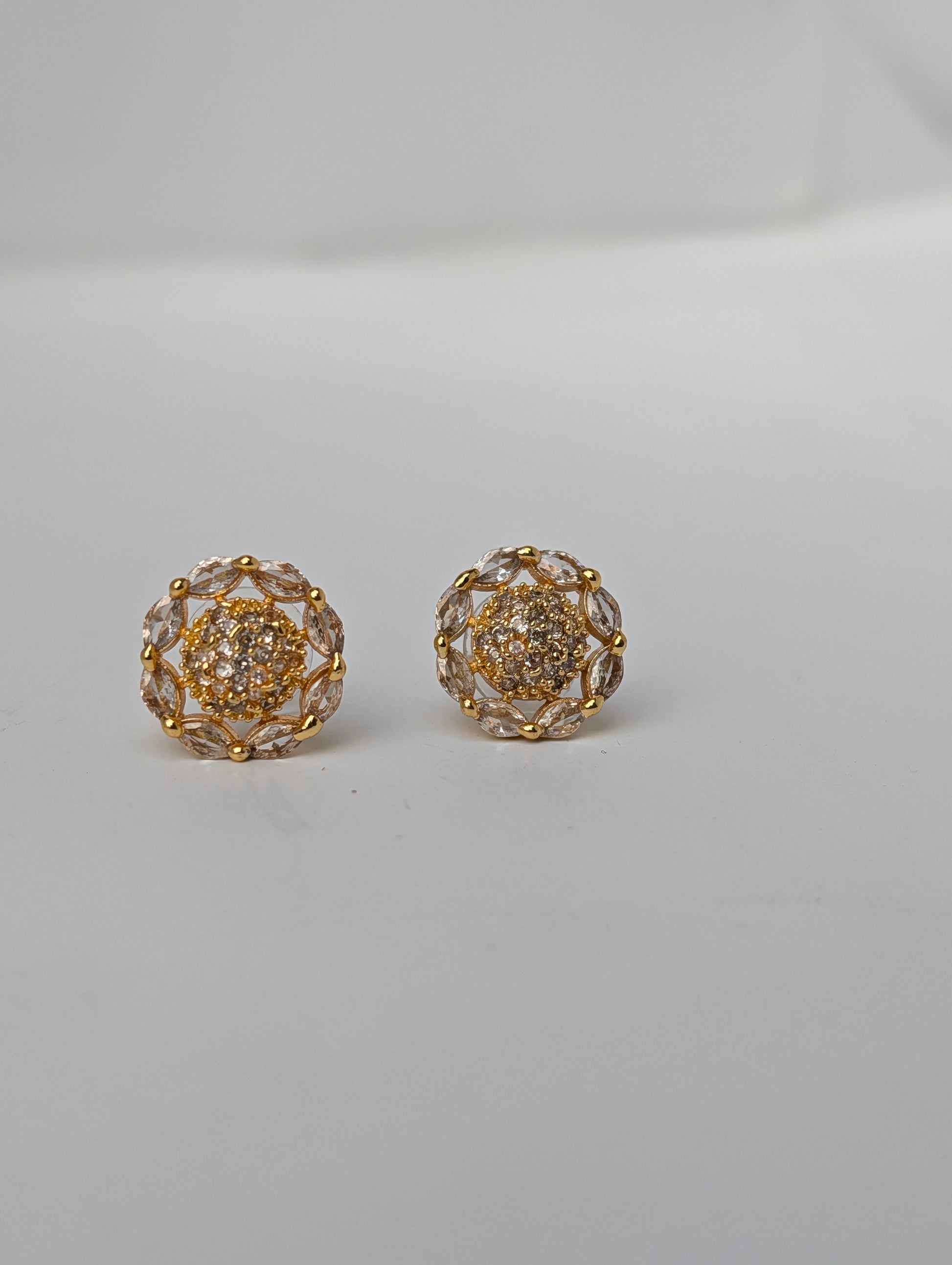 Pair of gold and crystal earrings on a light gray background
