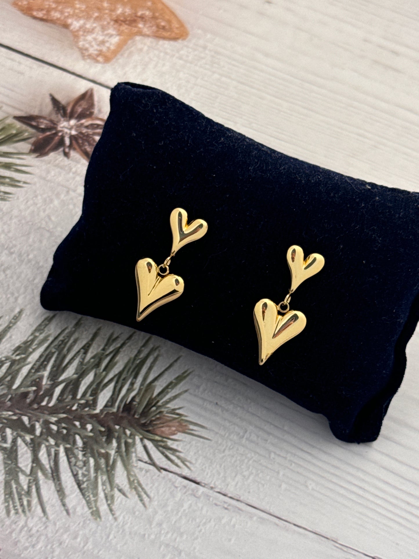 Gold antler-shaped earrings on a black cushion with a Christmas-themed background