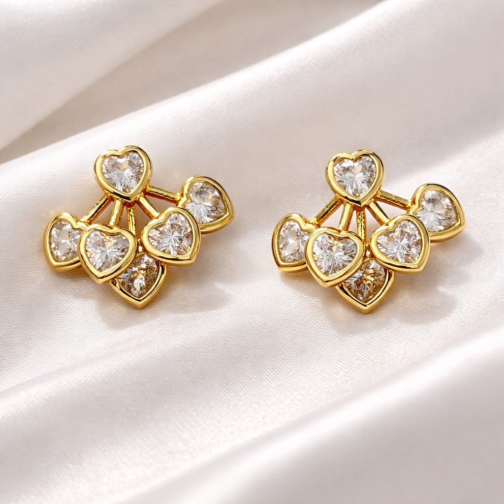 Gold earrings with heart-shaped gemstones on a white fabric background