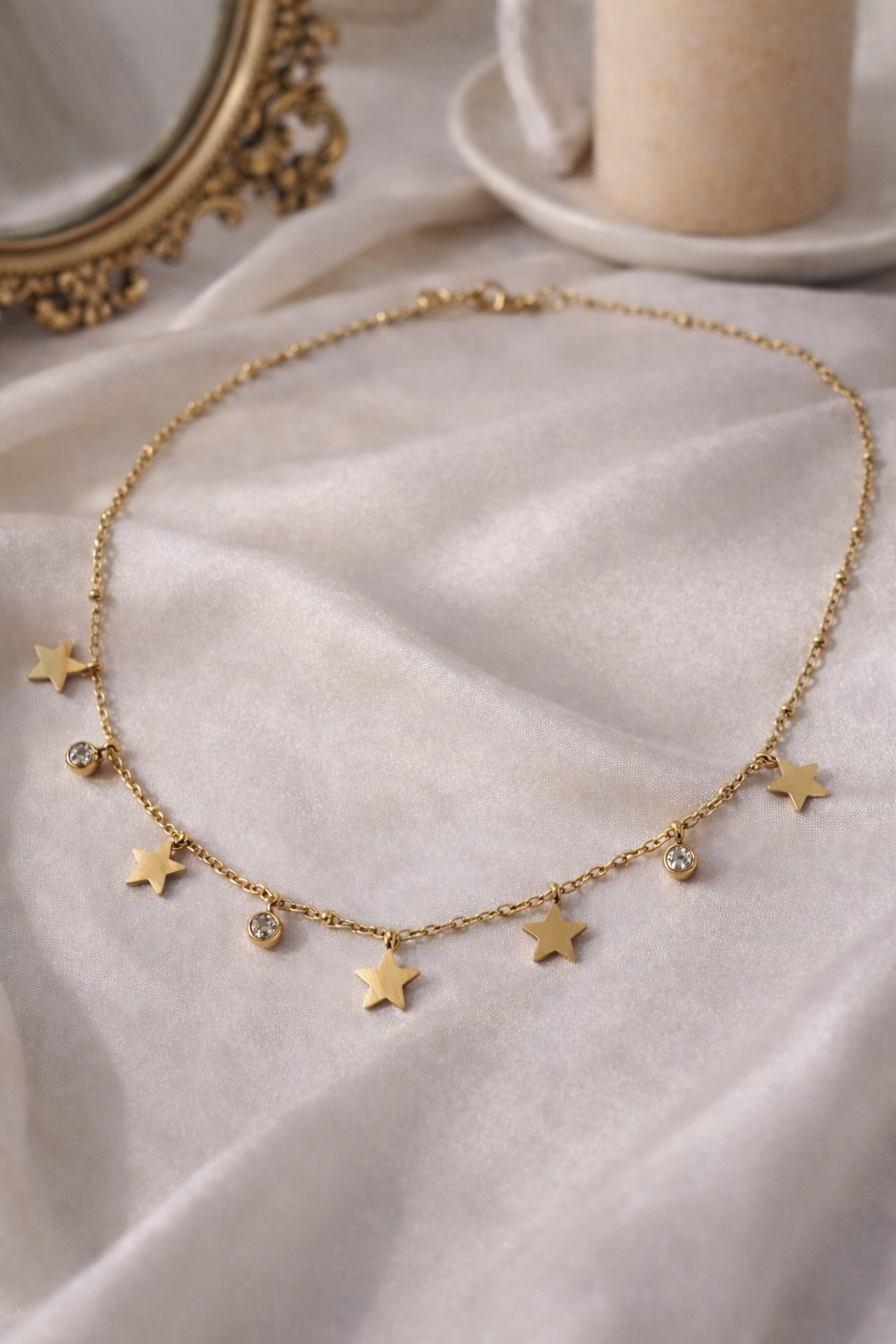 Gold necklace with star pendants on a light fabric background