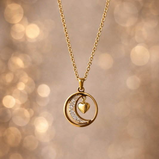 Gold necklace with a heart and moon pendant on a blurred golden background