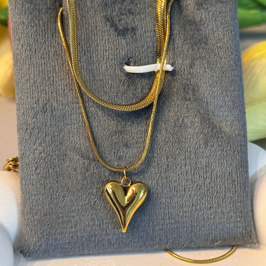 Gold necklace with a heart pendant on a gray surface