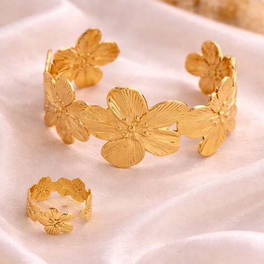 Gold floral bracelet and ring on a white fabric background