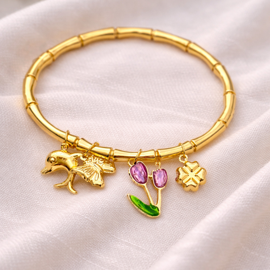 Gold bracelet with charms on a white fabric background