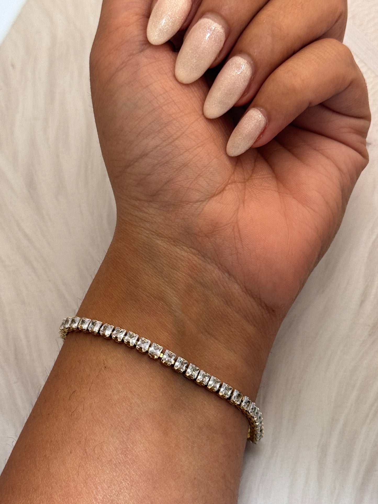 Hand wearing a bracelet on a light background