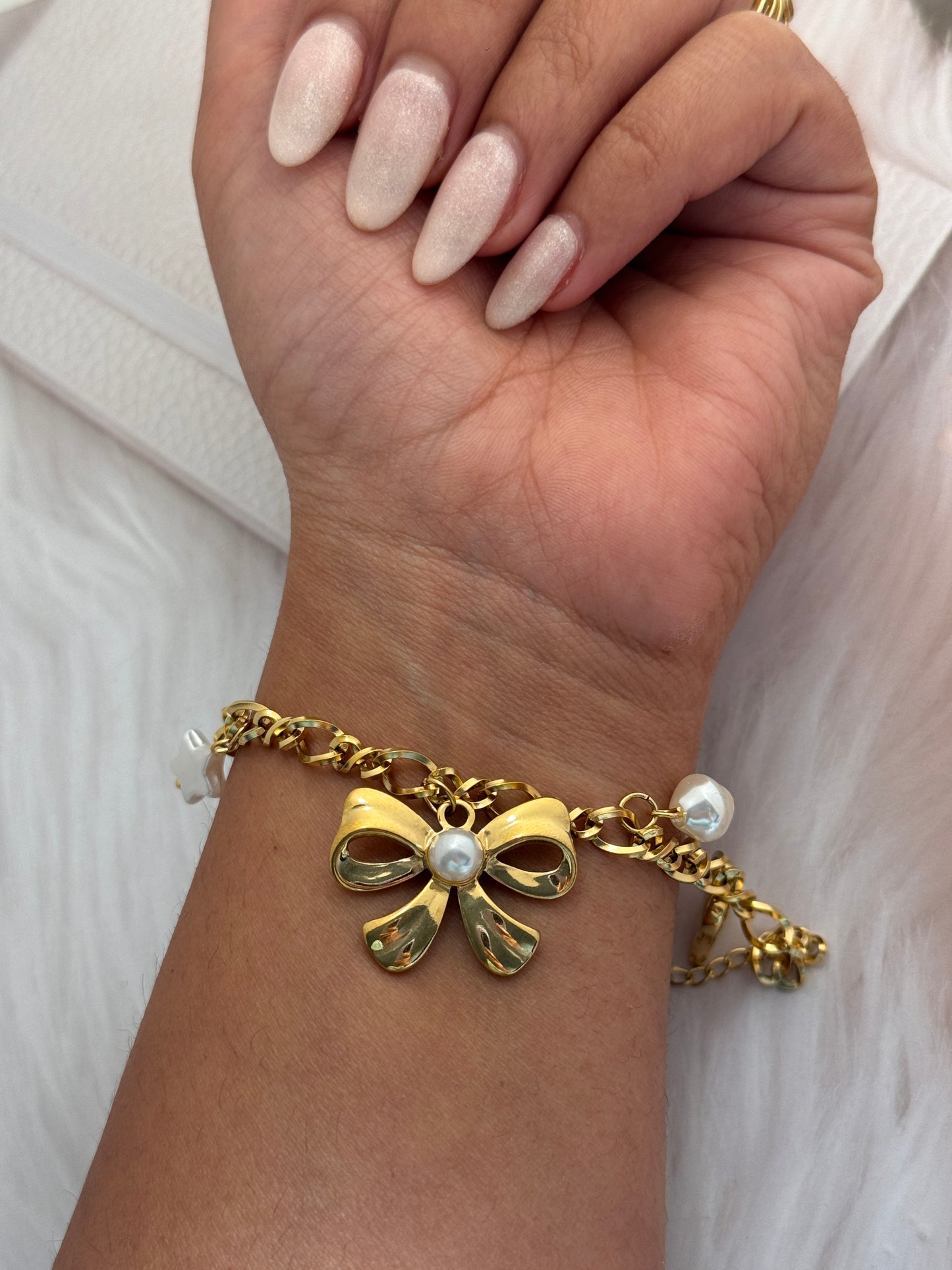 Gold bracelet with a floral design worn on a wrist against a white background